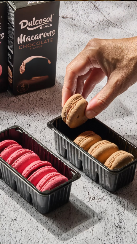 Fotógrafo gastronómico en Valencia – detalle de mano tomando macaron en set de repostería.